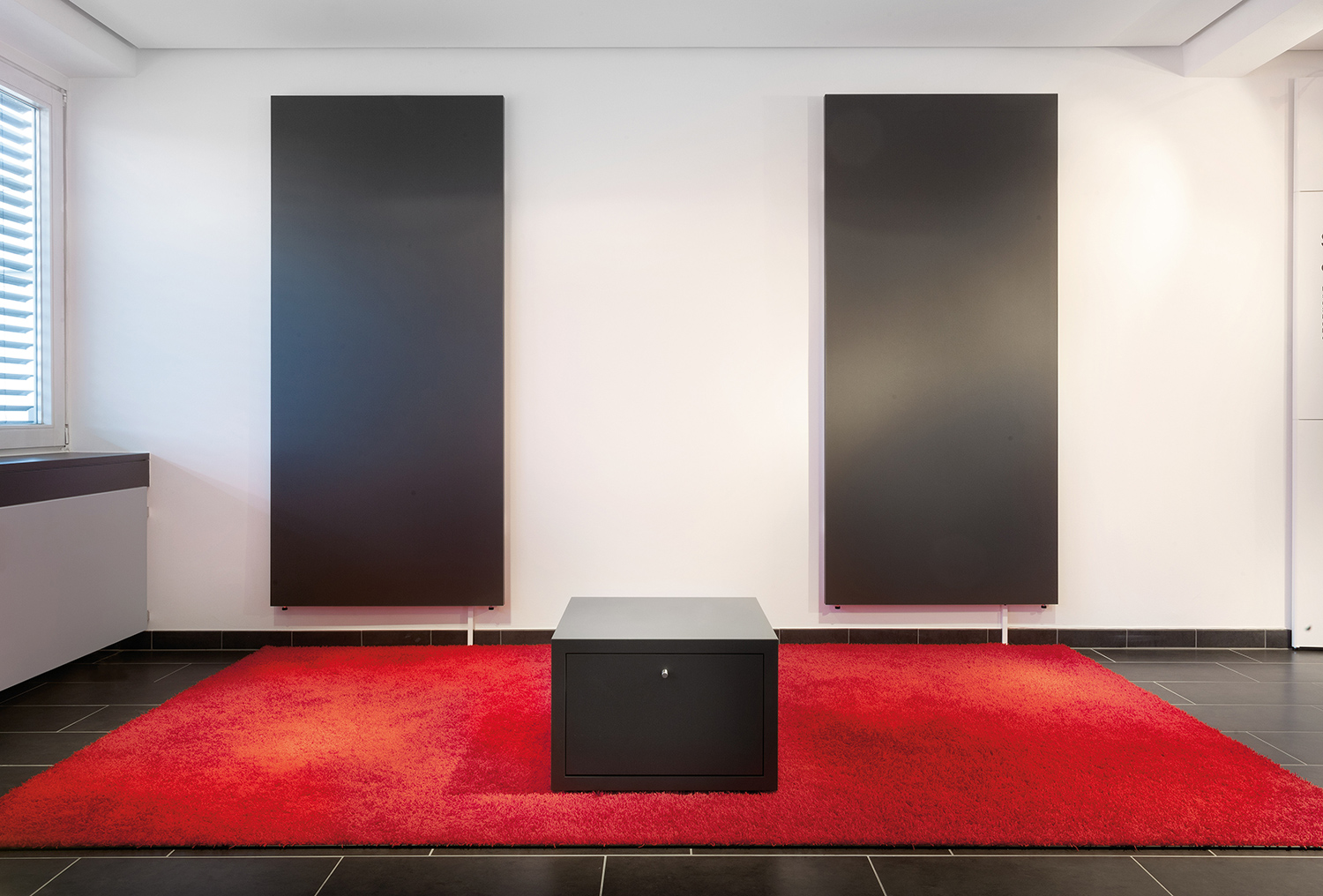 Aufbau Mila-wall Sound zur Live-Demo, zwei schwarze Wandmodule, eine schwarze Sitzgelegenheit auf rotem Teppich